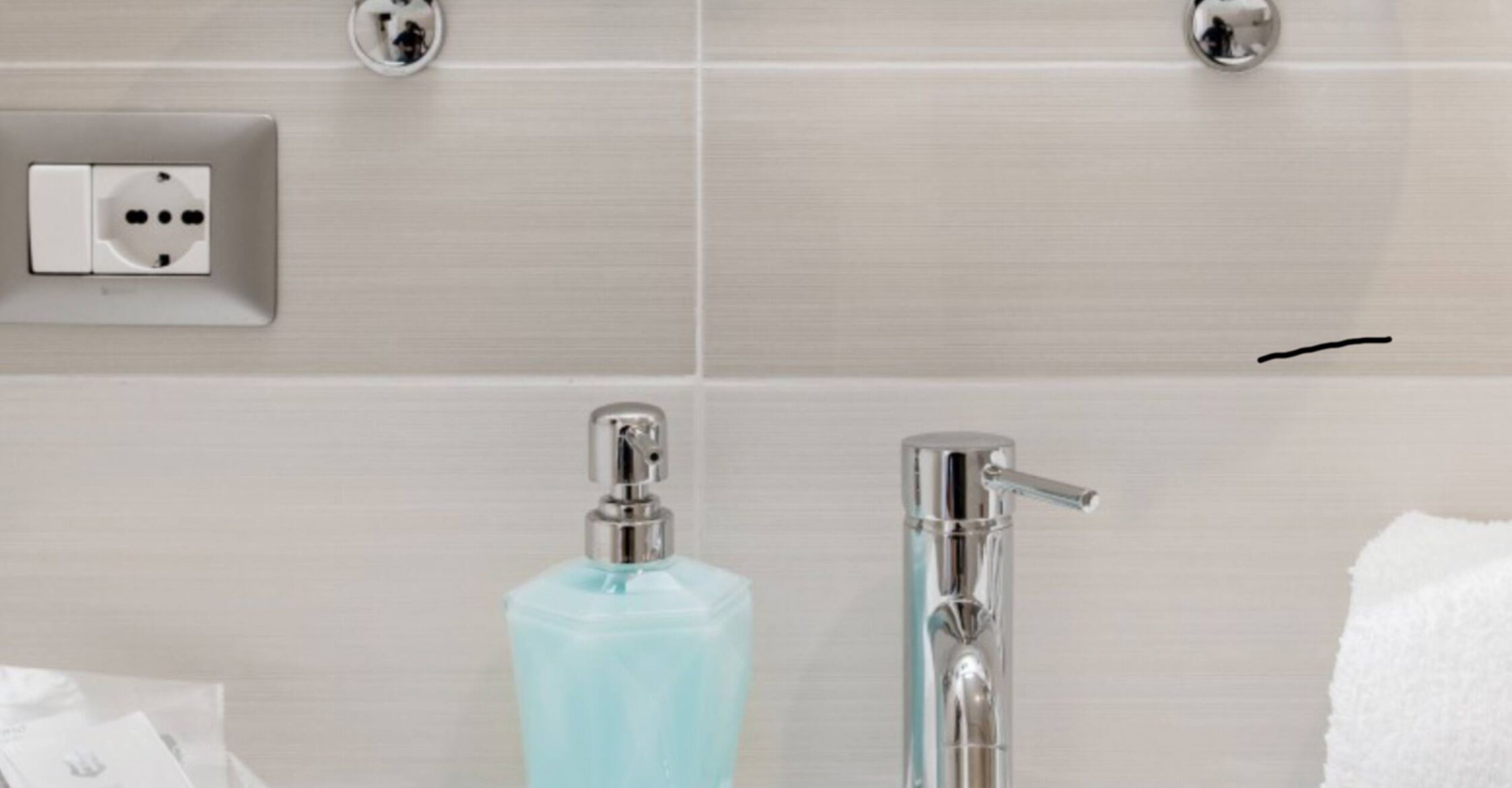 Un baño de diseño moderno, con dispensador de jabón azul claro y grifo de cromo.