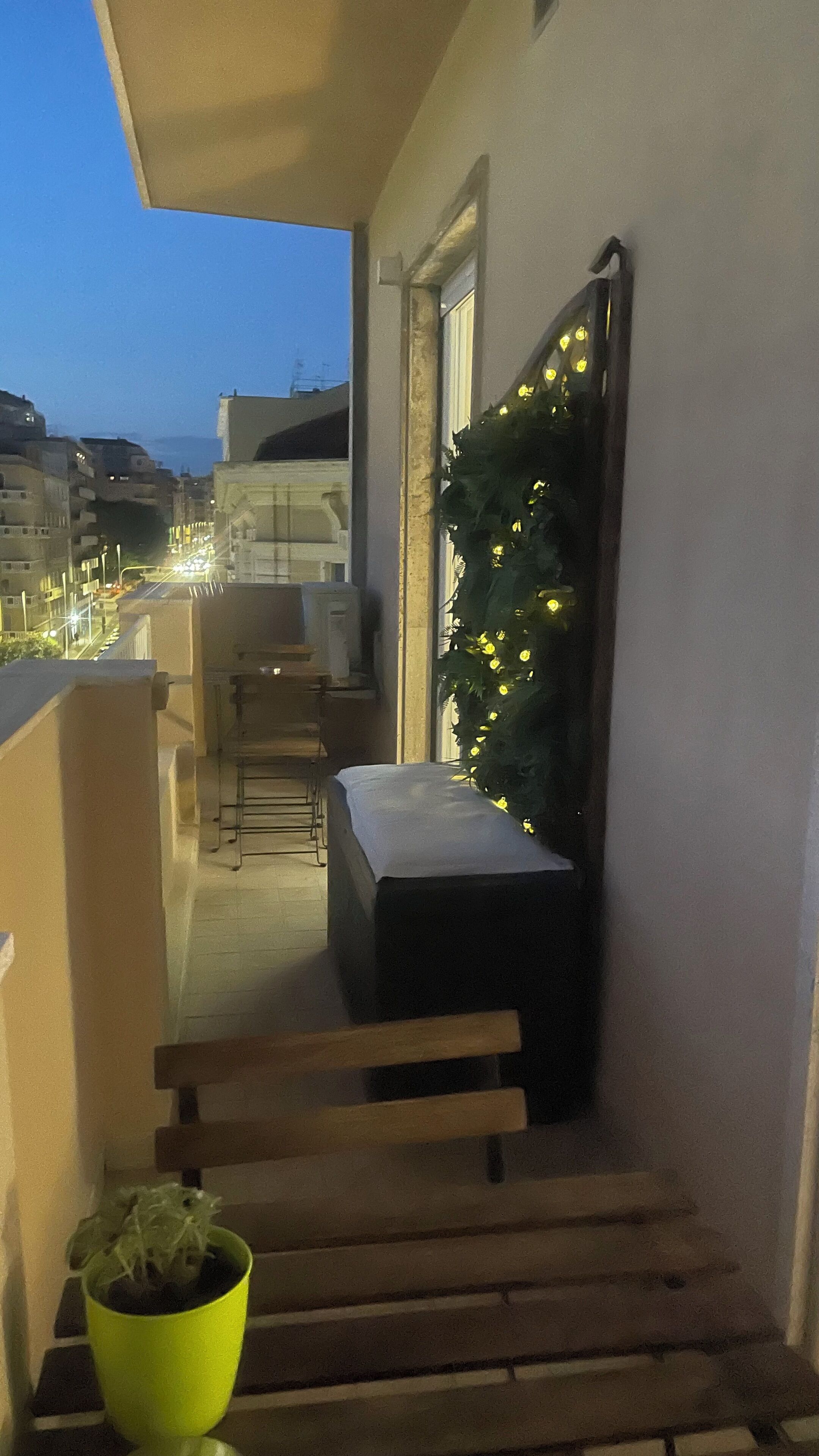 Een balkon met een bankje, een bloempot en een decoratie aan de muur.