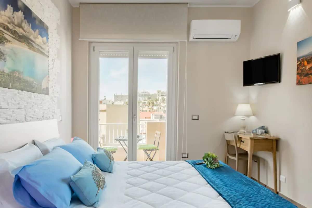 Una camera da letto con un letto, una scrivania, una sedia, un condizionatore d'aria e una TV.