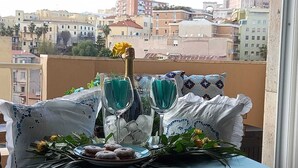 A table with a glass of water, two glasses of a blue beverage, a plate of pastries, and a yellow flower. - Cagliari Magica (Cagliari)