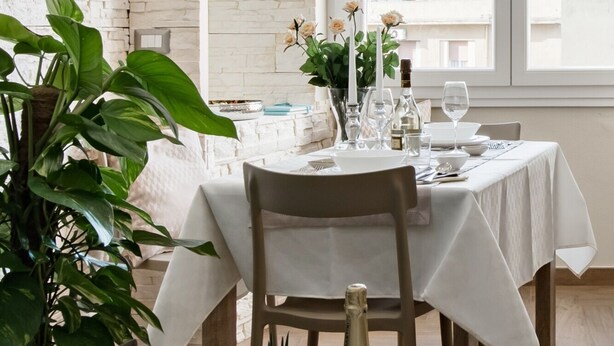 A dining table set with white tablecloth, candles, and a vase of flowers. - Cagliari Magica (Cagliari)