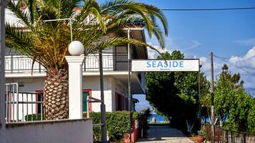 Schild für 'SEASIDE Resorts' mit Blick auf ein Gebäude und eine Palme im Vordergrund.