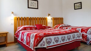 Una habitación con dos camas, cabecero de madera, paredes blancas y dos cuadros enmarcados.