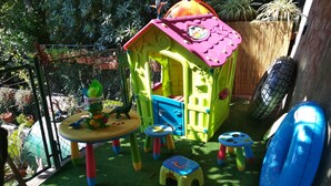 A children's play area with a small house, play tables, and toy vehicles. - Guest House Tomanovic (Herceg Novi)