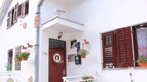 A building with a wooden door, potted plants, and a white railing. - Guest House Tomanovic (Herceg Novi)