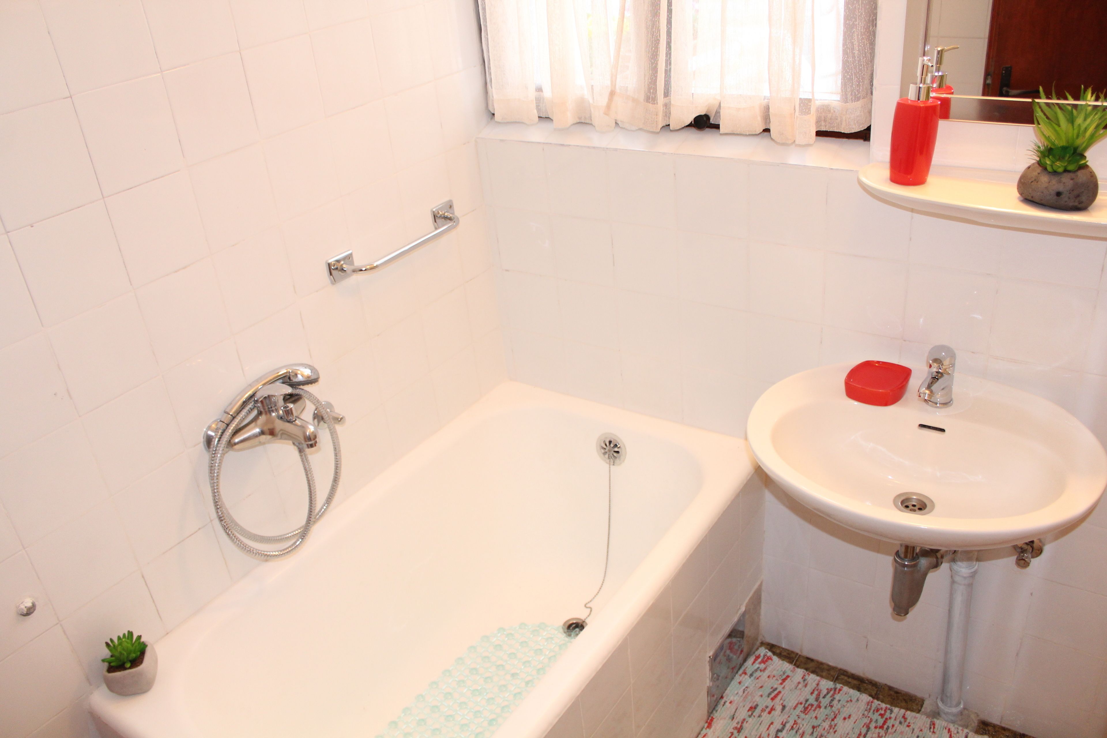 Un baño con bañera, lavamanos y ventana con cortinas.