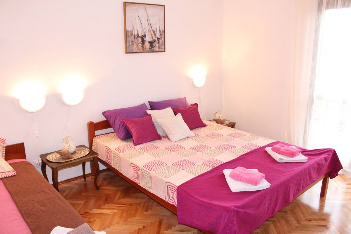 Une chambre d’hôtel avec un grand lit, deux tables de chevet, un plancher en bois et un tableau au mur.
