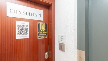 Una puerta con la leyenda 'CITY SUITES 1', un código QR, una credencial de seguridad y un lector de tarjetas.