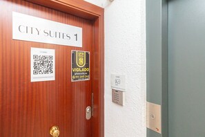 Una puerta con la leyenda 'CITY SUITES 1', un código QR, una credencial de seguridad y un lector de tarjetas.