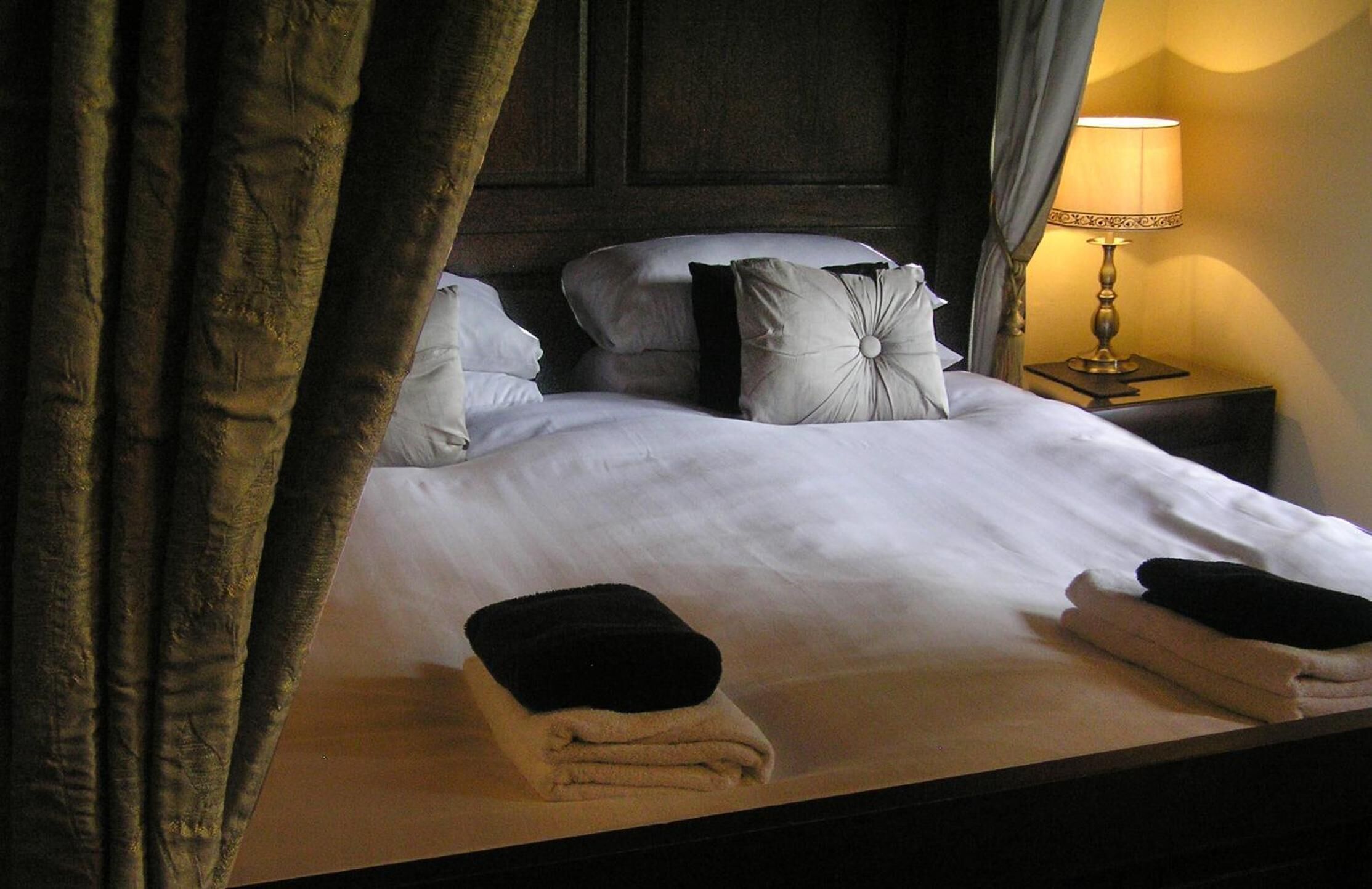 A neatly made bed with white linens, two pillows, and a folded towel on the side.