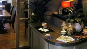 Un espace d’accueil d’hôtel comprenant un comptoir, des chaises, une plante et une lampe.