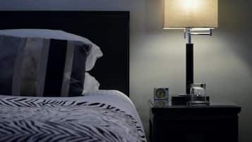 Un dormitorio con cama, mesita de noche, lámpara y reloj.