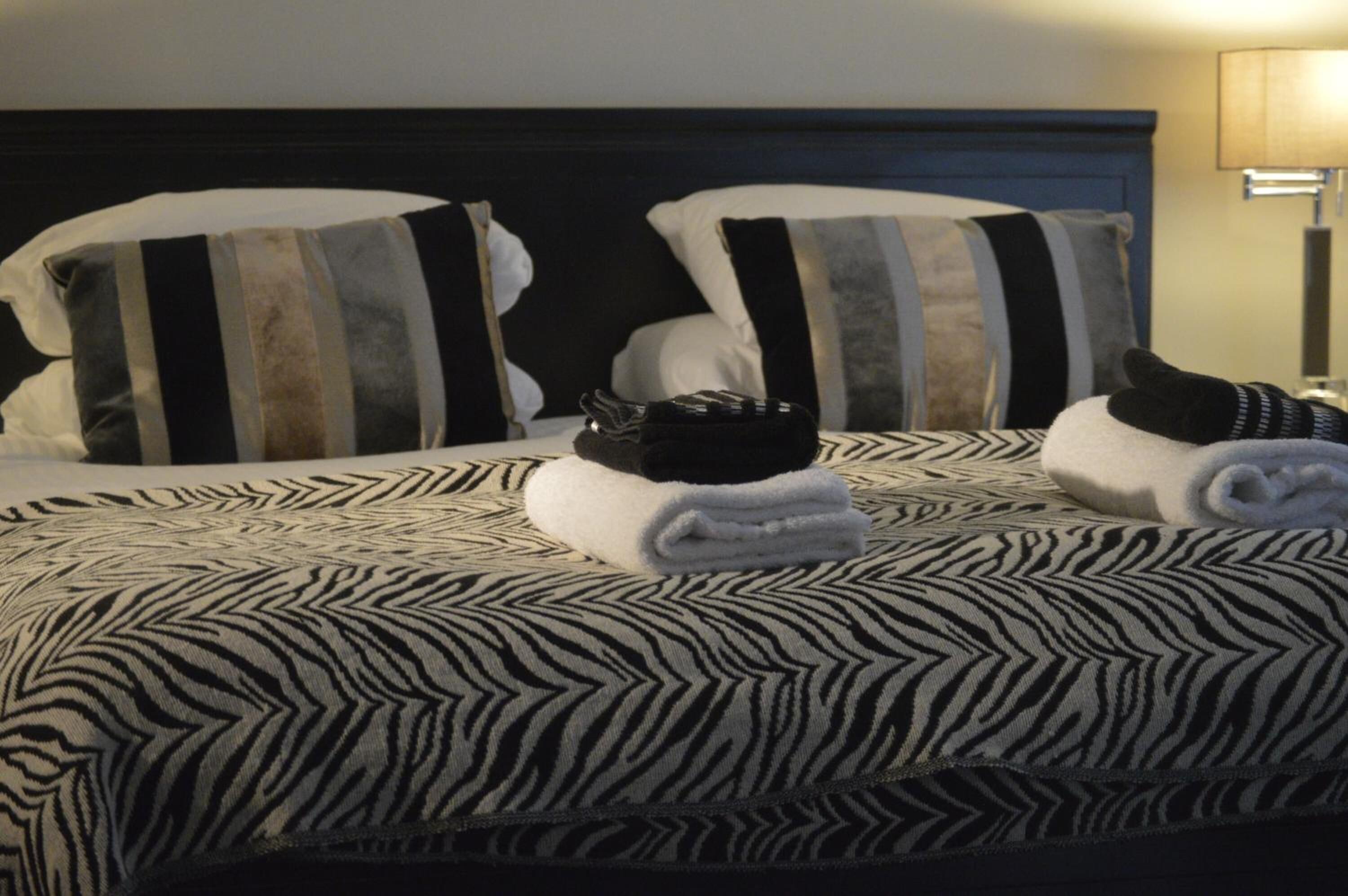 A neatly made bed with striped pillows and a zebra-patterned bedspread.
