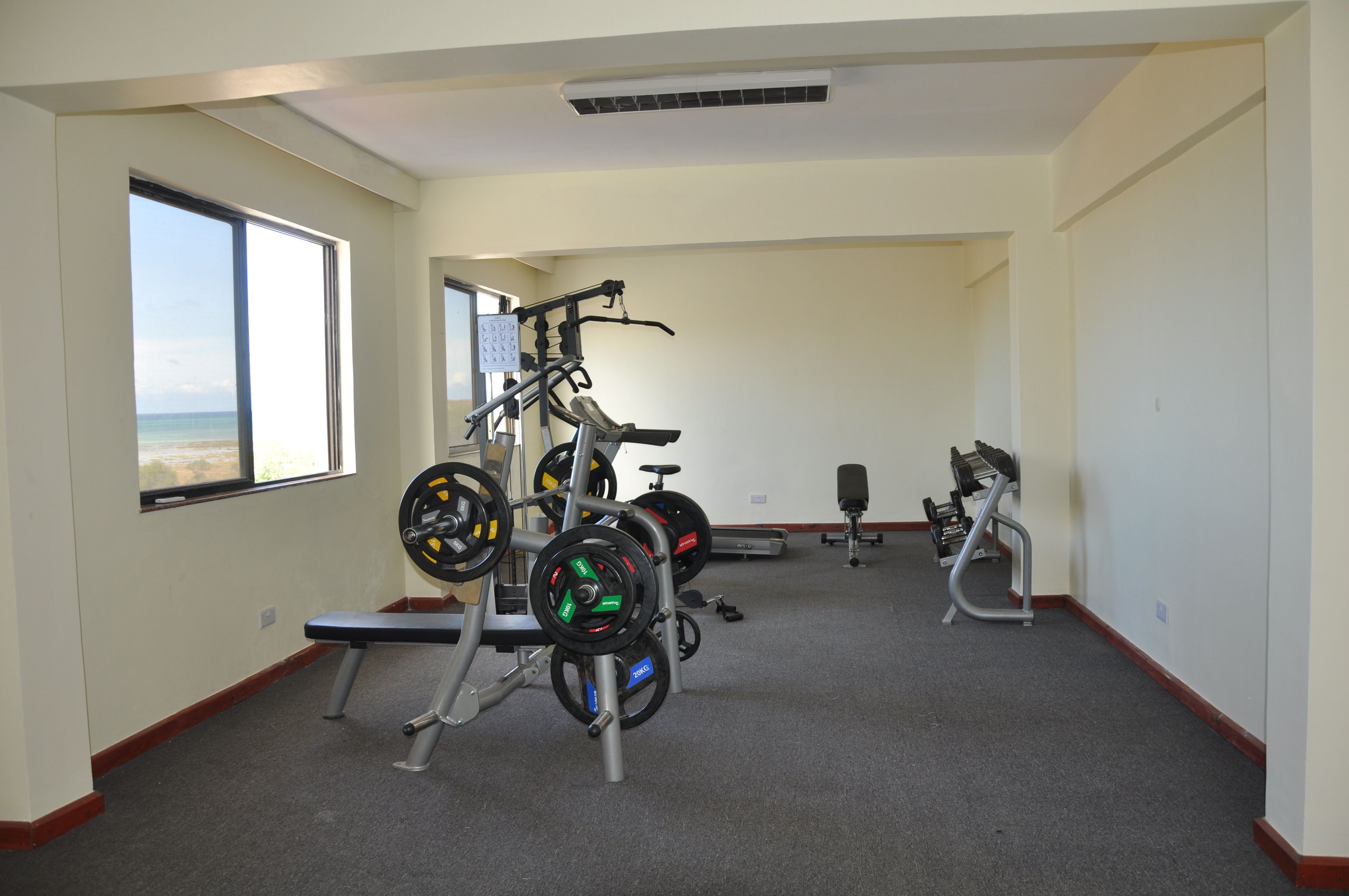 A gym with weightlifting equipment, a bench, and a treadmill.