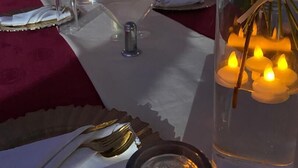 Une table dressée pour un événement formel, agrémentée de compositions florales, de bougies et de verres transparents.