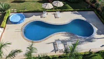 Una piscina al aire libre, sombrillas, sillones reclinables de piscina
