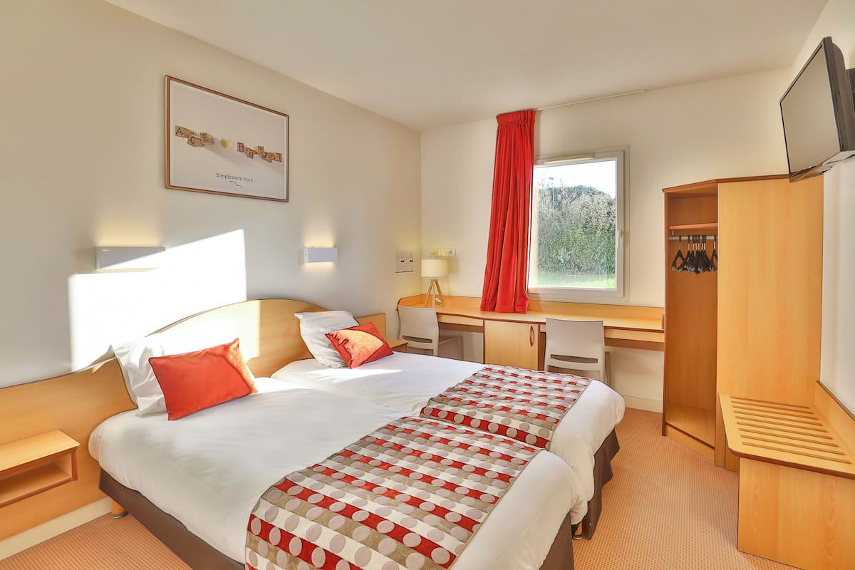 Une chambre d’hôtel avec un lit, un bureau et une armoire.