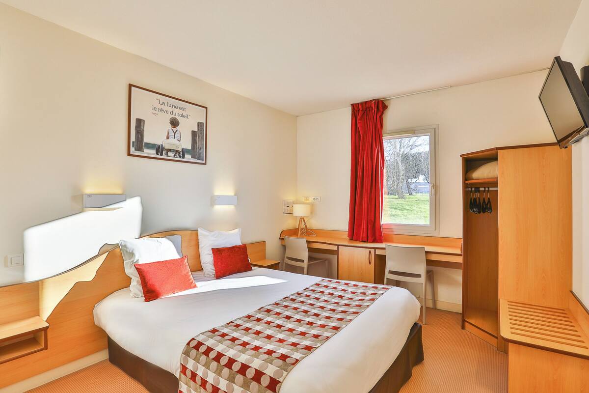 Une chambre d’hôtel équipée d’un lit, d’un bureau, d’une chaise, d’une armoire et d’un téléviseur.