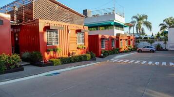 Un edificio moderno con fachada roja, amplios ventanales y un estacionamiento con un automóvil.