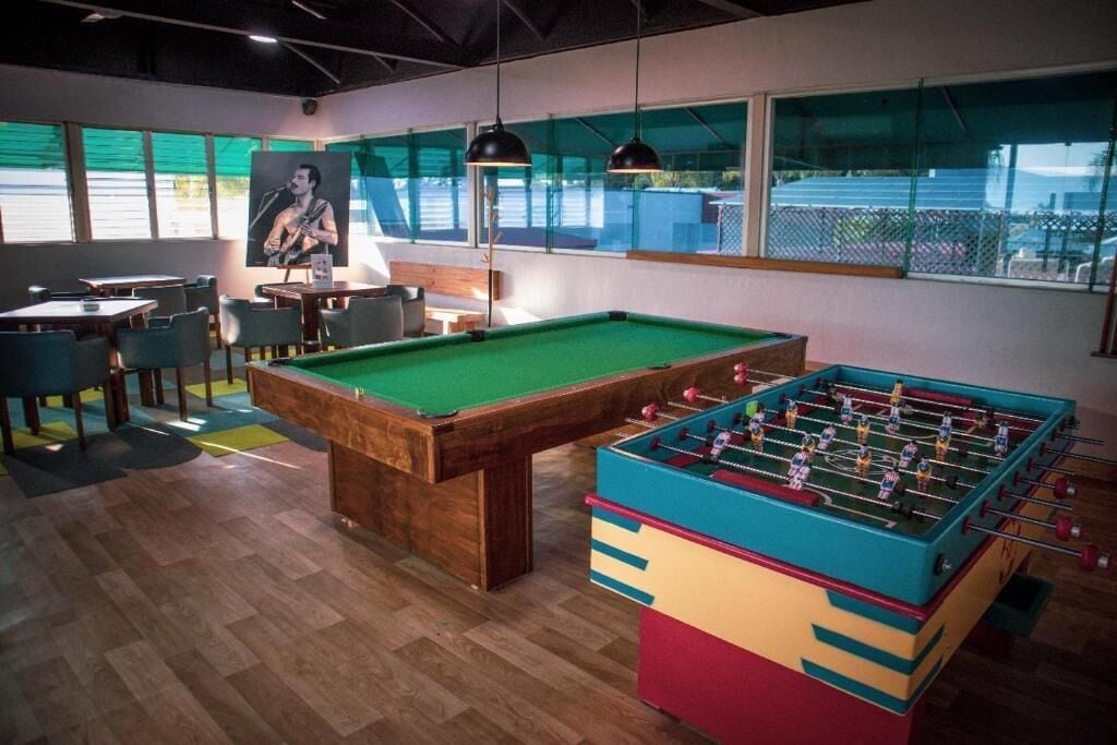 Una mesa de billar, una mesa de futbolín y una zona de estar con mesas y sillas.