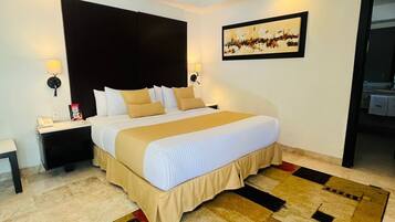 Habitación de hotel con cama, mesitas de noche, una obra de arte en la pared y una alfombra estampada.