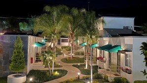 A modern hotel with a landscaped courtyard featuring palm trees, a central fountain, and outdoor seating areas. - Hotel del Pescador (Jocotepec)