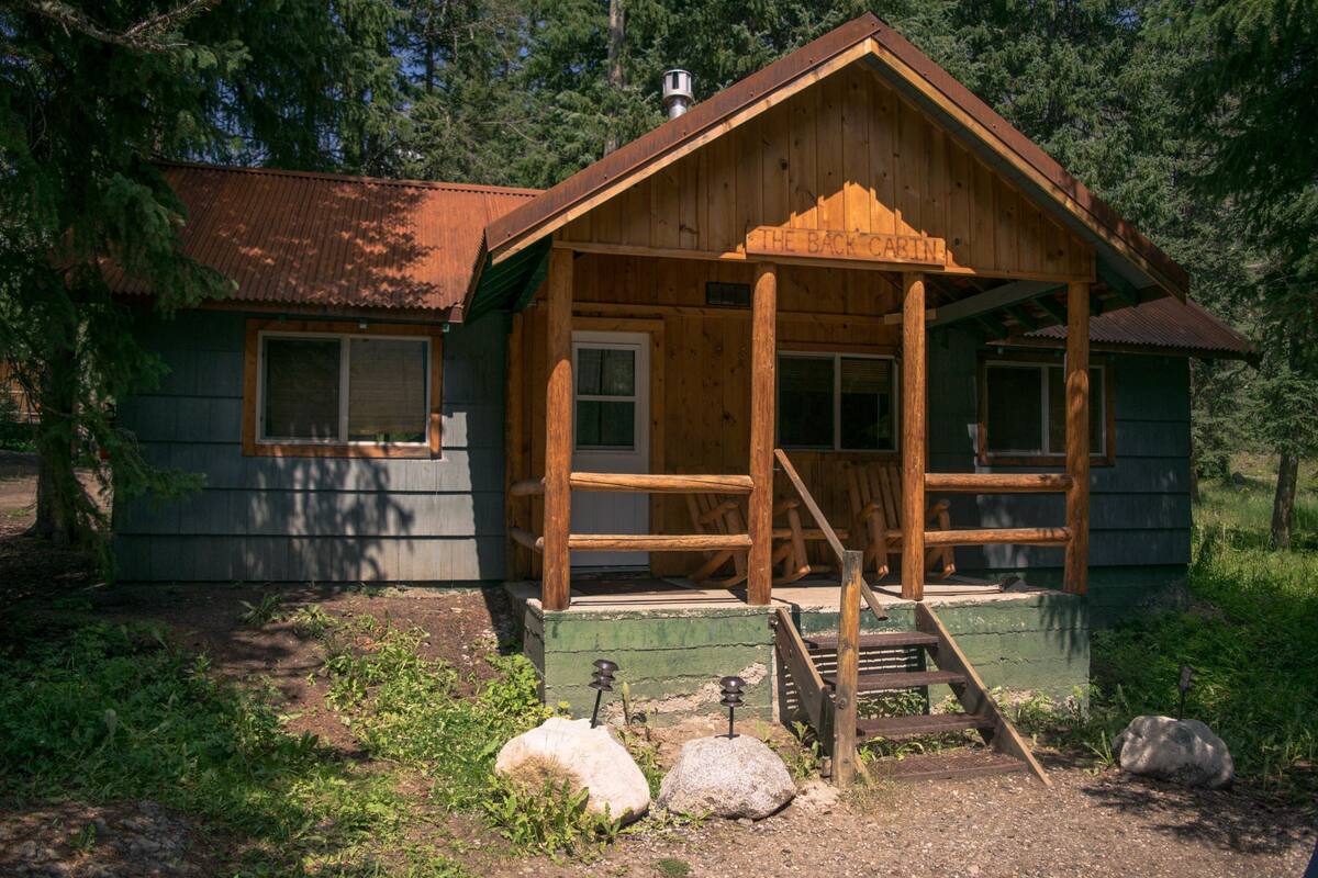 A wooden cabin with a porch, a front door, and a chimney.
