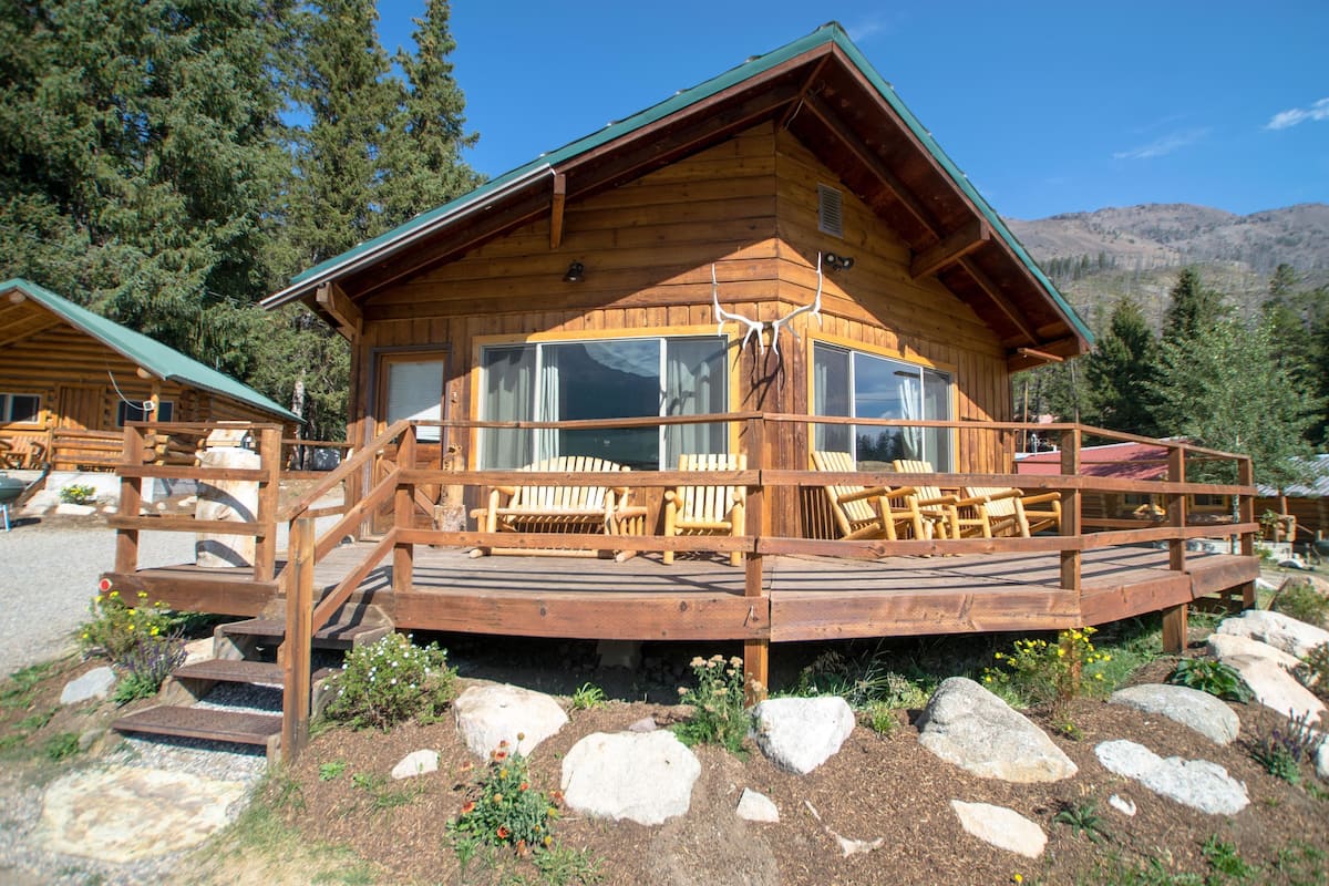 A wooden cabin with a deck and outdoor seating area.