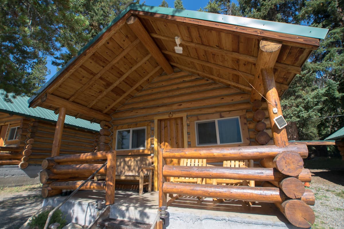 A log cabin with a wooden exterior, a metal roof, and a front porch.