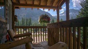 A wooden porch with a view of mountains and a hanging flower basket. - Silver Gate Lodging (Silver Gate)