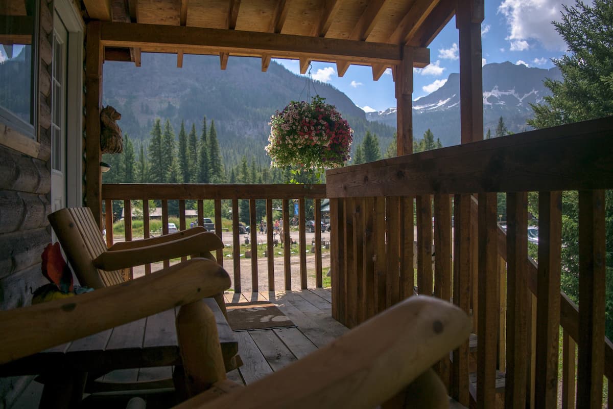 A wooden porch with a view of mountains and a hanging flower basket.