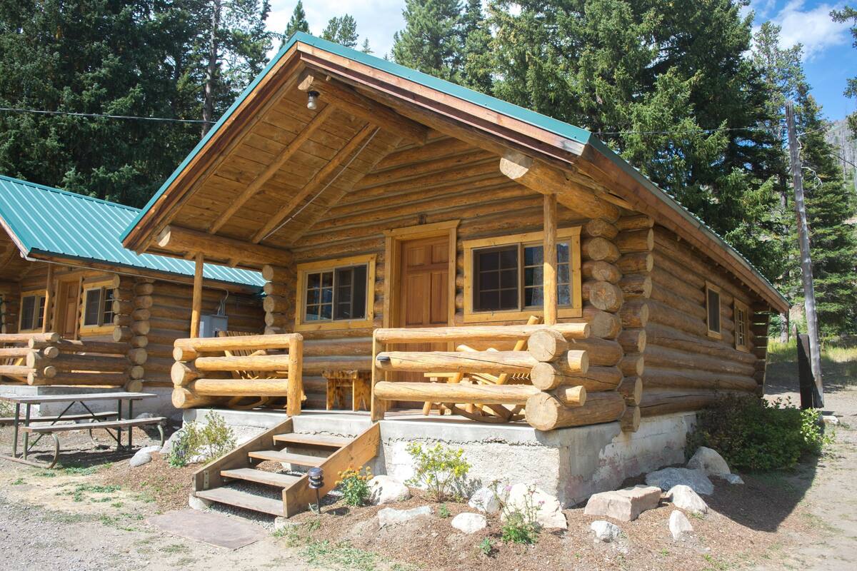 A log cabin with a porch, a picnic table, and a staircase leading to the entrance.