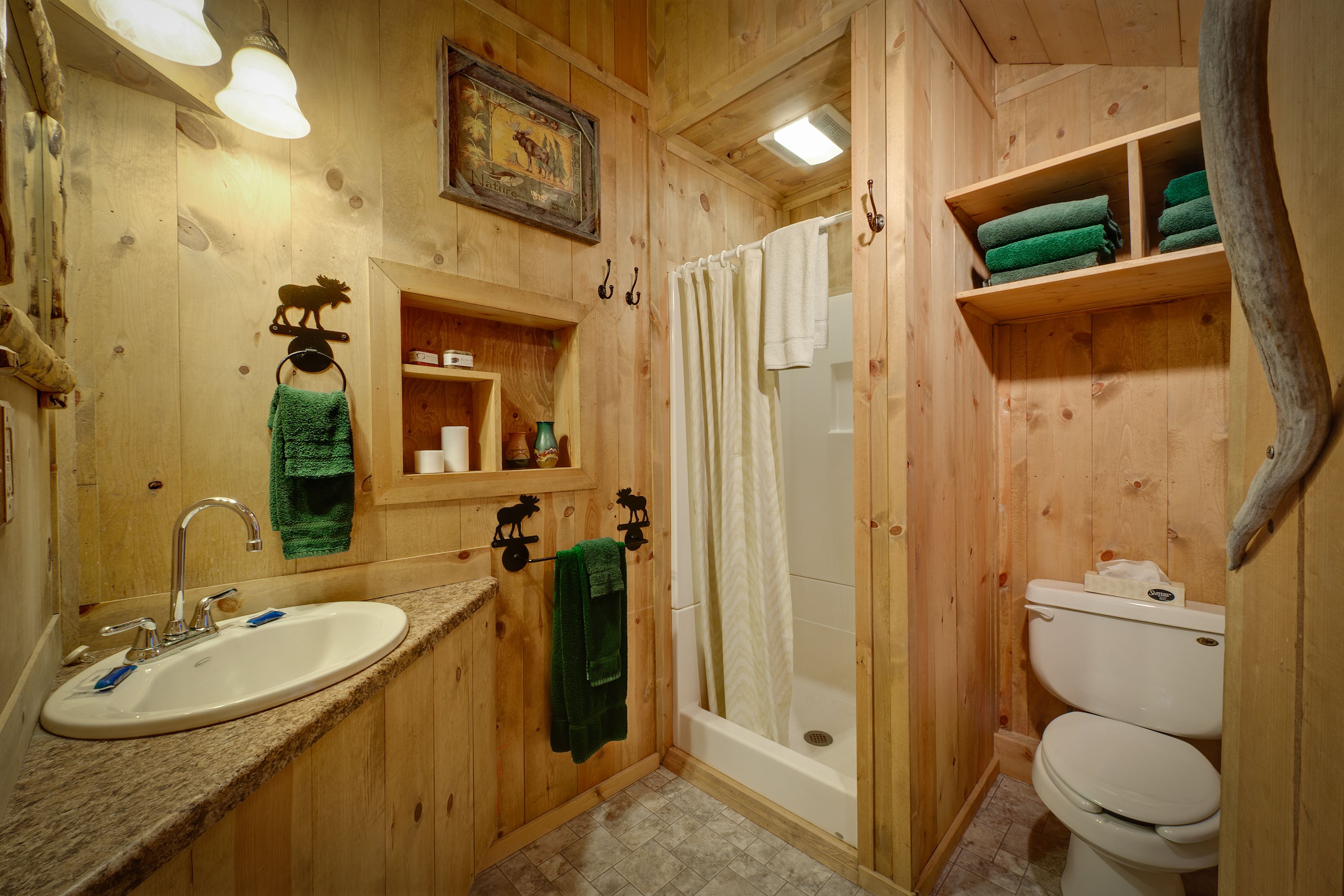 A wooden cabin bathroom with a sink, toilet, and shower.