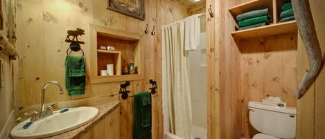 A wooden cabin bathroom with a sink, toilet, and shower.