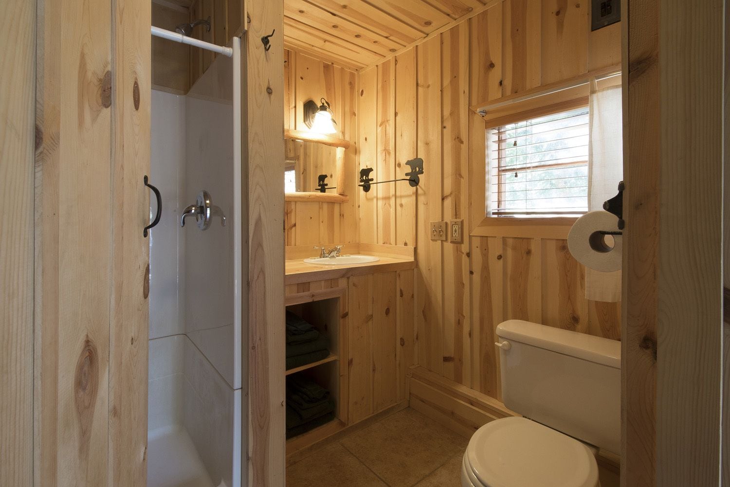 Un baño con paneles de madera, que incluye un inodoro, lavabo y ducha.
