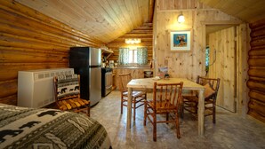 A log cabin interior with a dining area, kitchen, and a cozy fireplace. - Silver Gate Lodging (Silver Gate)