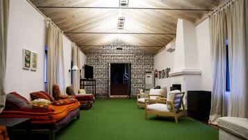 A cozy room with a green carpet, wooden furniture, and a patterned wall.