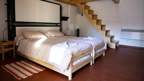 A bedroom with a wooden bed, a wooden staircase, a white wall, and a tiled floor. - Hostel Layos, Toledo (Layos)
