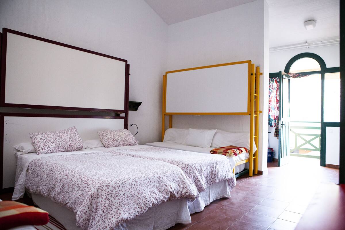 Habitación de hotel con dos camas, un ventanal grande y un balcón.