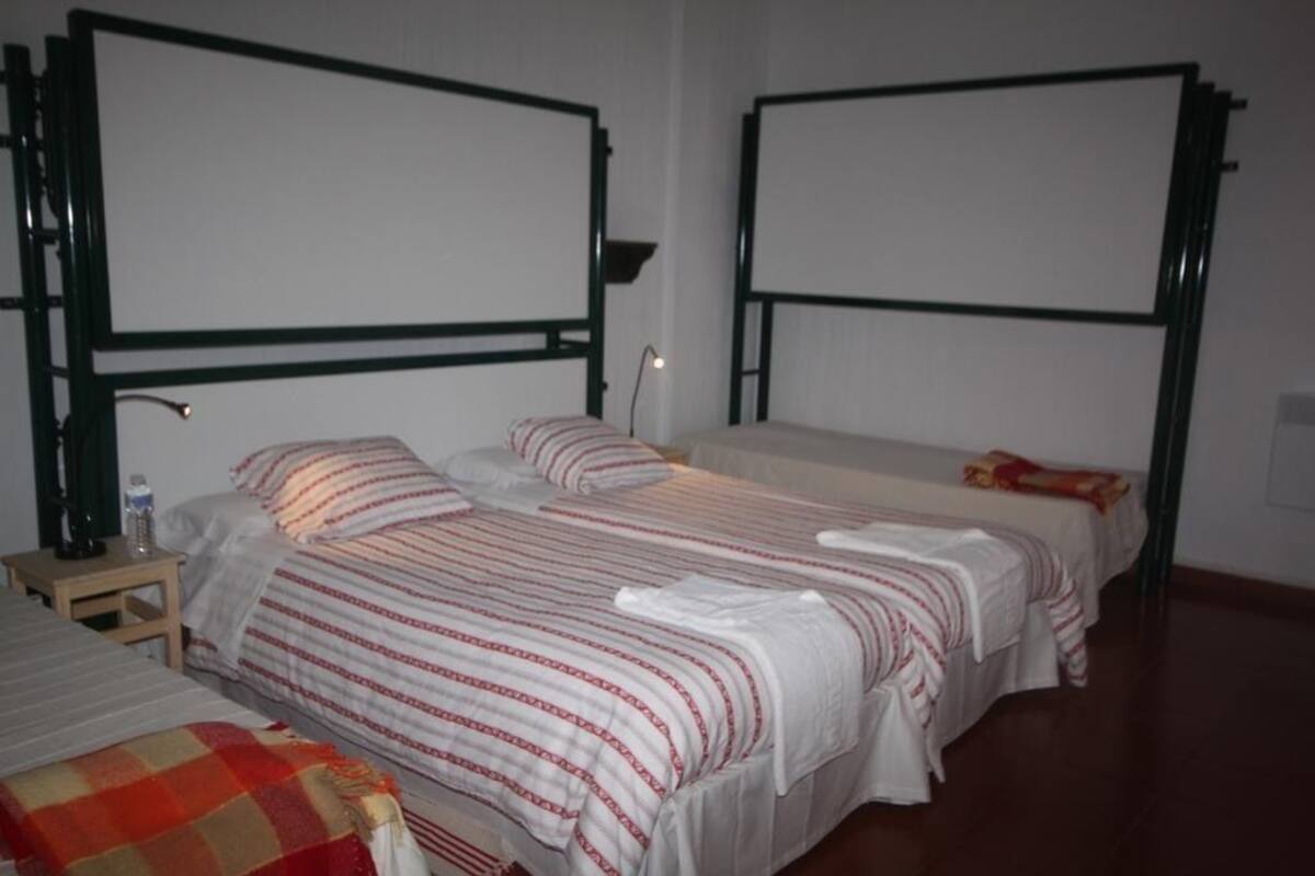 Una habitación de hotel con dos camas, cada una con cabecera y mesita de noche.