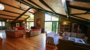 A spacious loft with high ceilings, wooden floors, and a large open living area with multiple seating options and a bookshelf. - Hostel Layos, Toledo (Layos)