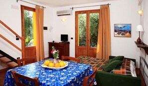 Una habitación con una mesa de comedor dispuesta con fruta, un sofá y un cuadro en la pared.