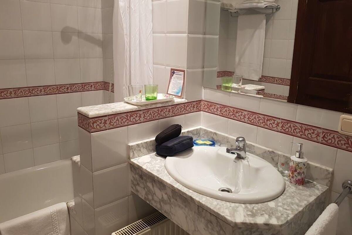 A bathroom with a marble sink, a mirror, a towel rack, and a shower curtain.
