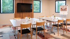 Une salle de conférence équipée d’un grand téléviseur à écran plat, de plusieurs tables, de chaises et d’une affiche accrochée au mur.