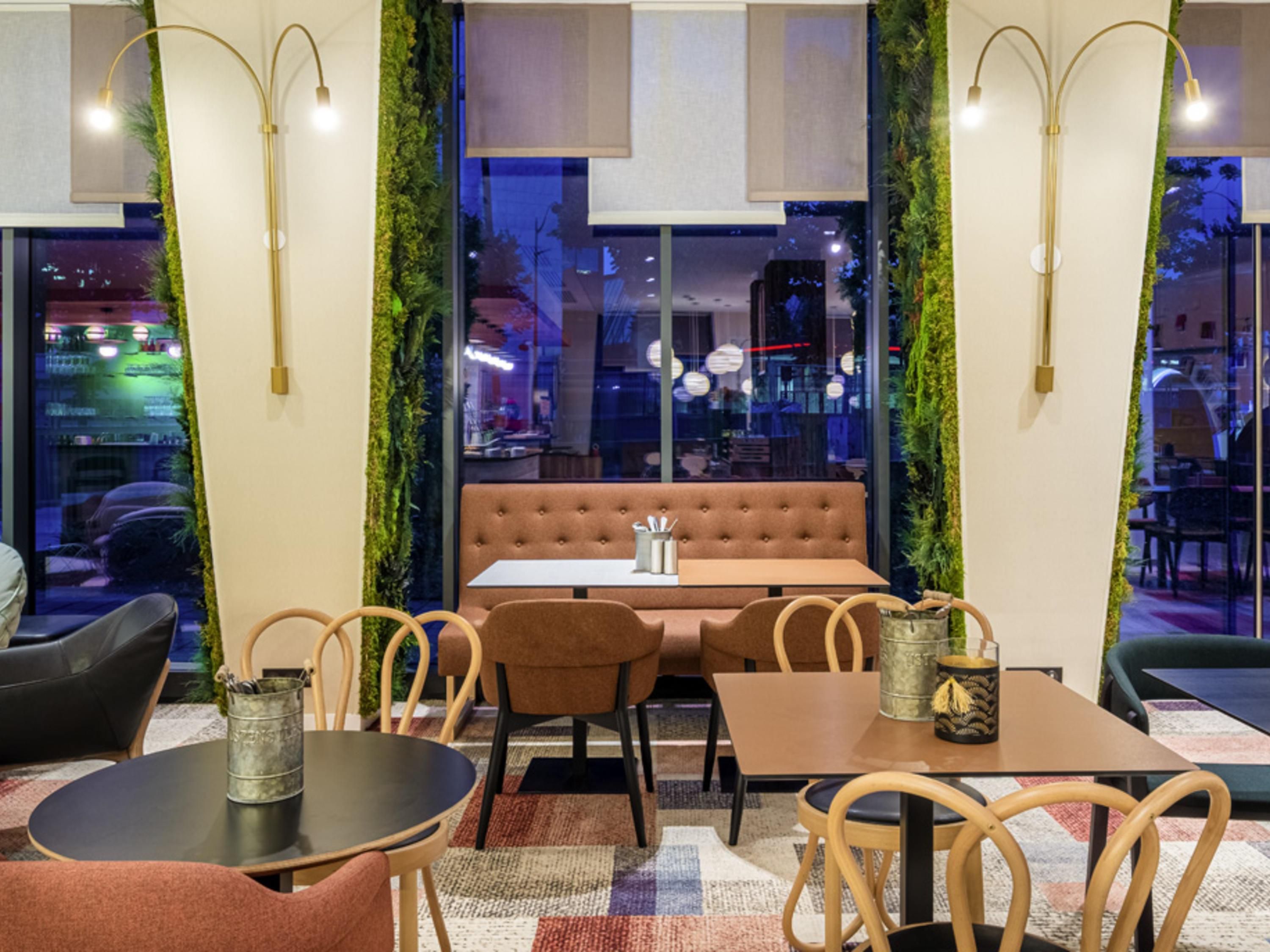 A restaurant interior with a booth seating area, tables, chairs, and a view through a window.