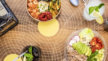 Une table avec deux bols de nourriture, un verre de boisson fraîche et des couverts.