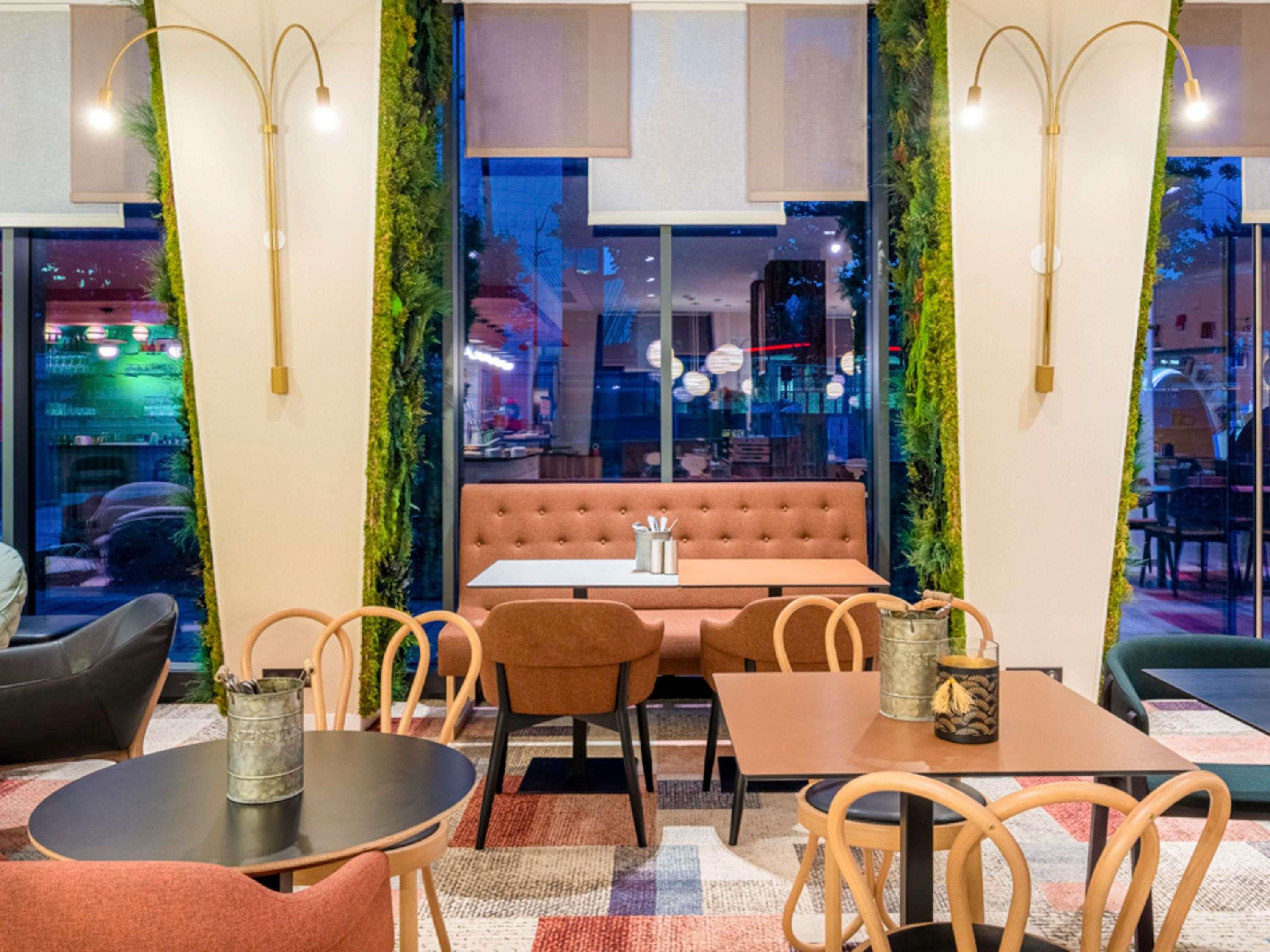 A cozy restaurant interior with a cushioned booth, wooden chairs, and tables.