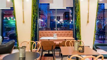 A cozy restaurant interior with a cushioned booth, wooden chairs, and tables.