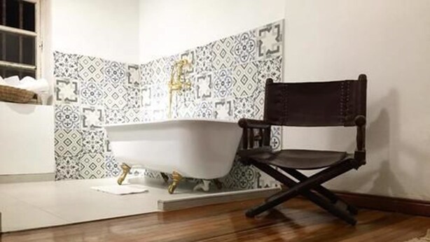 A bathroom with a freestanding bathtub, a wooden chair, and patterned tiles on the walls. - Casa Boutique Villa de Leyva - Adults only (Villa de Leyva)