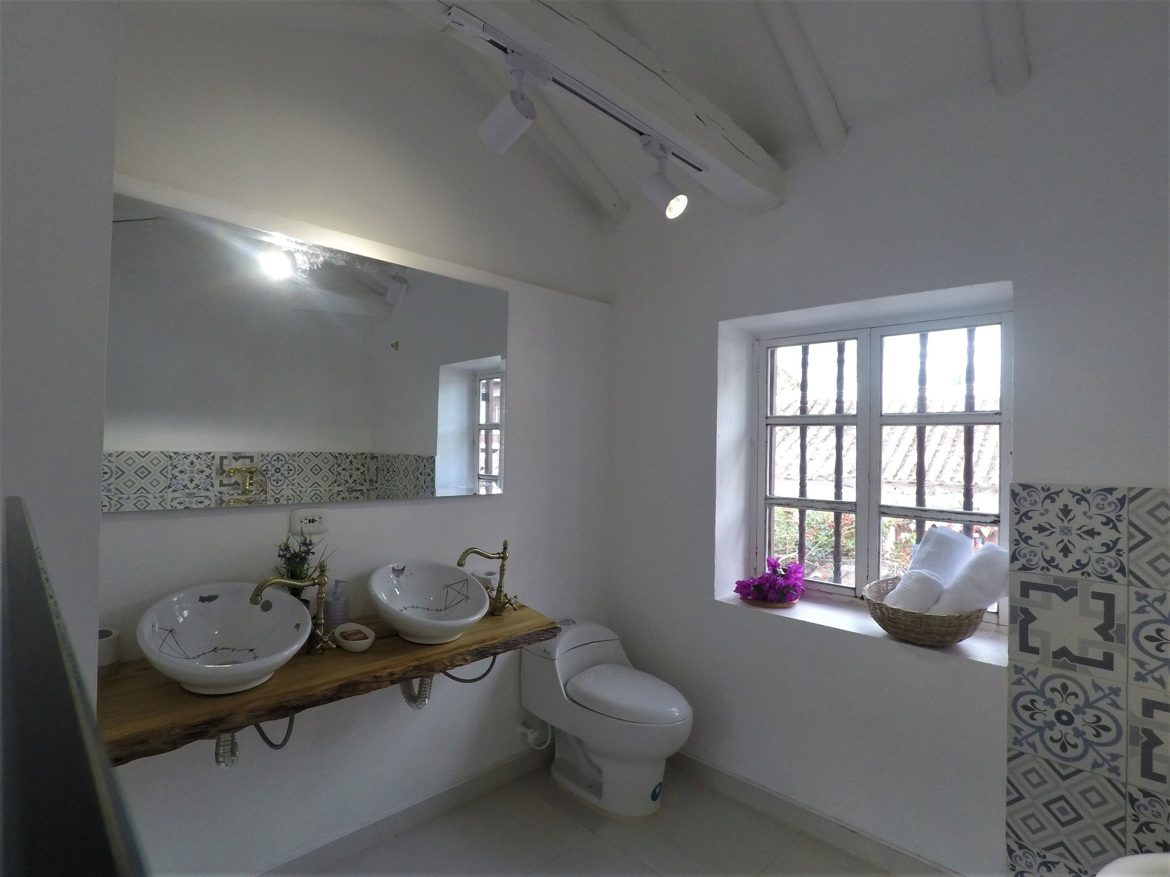 A bathroom with two sinks, a toilet, a window, and a mirror.